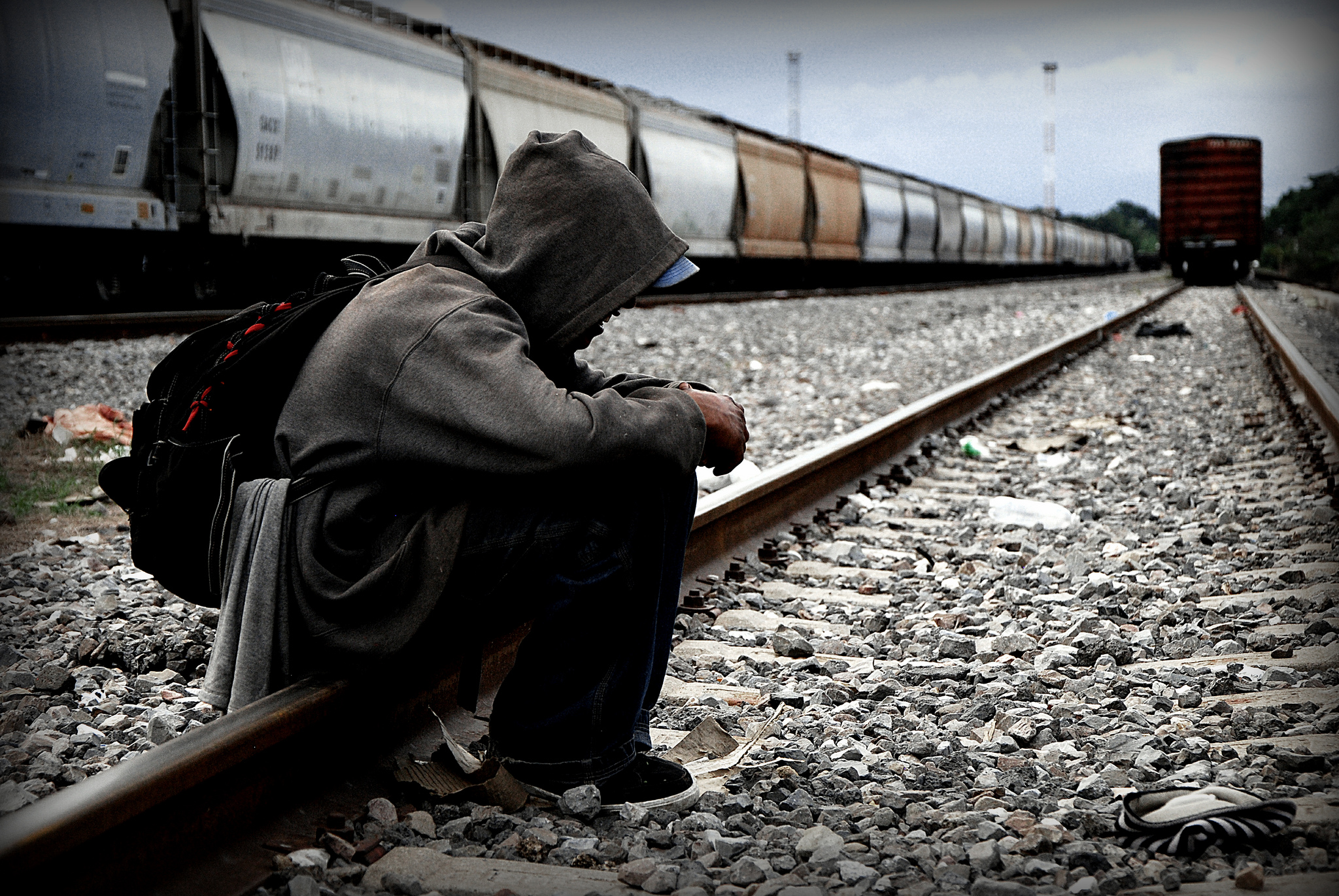 Migrante sentado, vías de tren