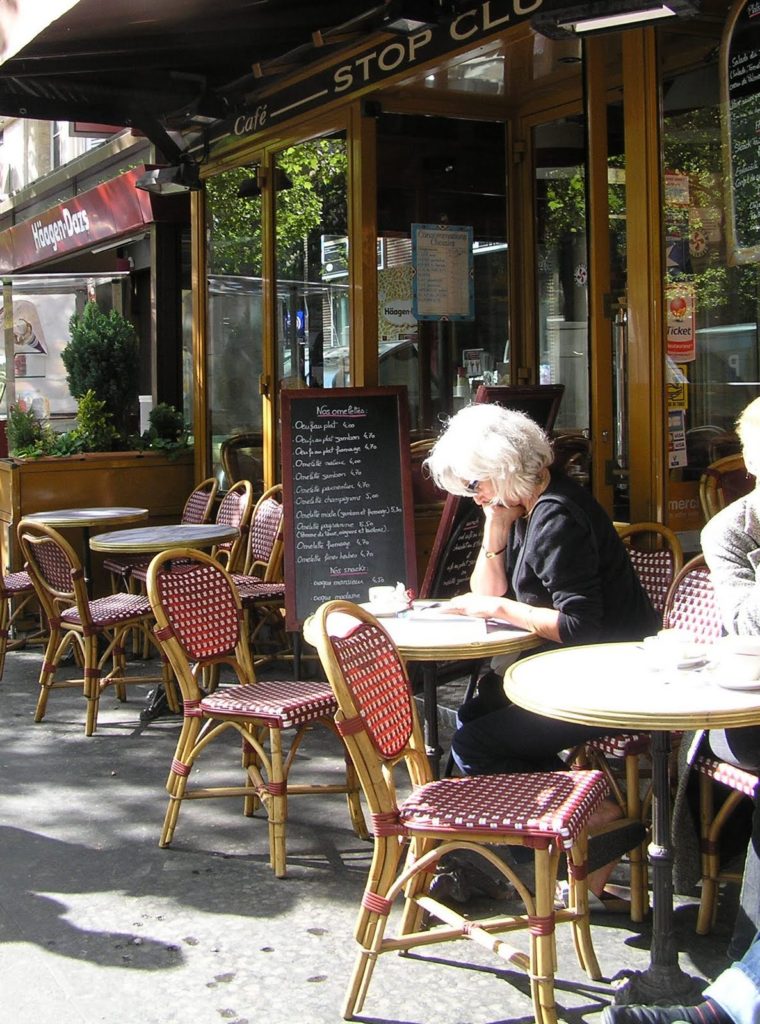 Mujer leyendo en un café de París.