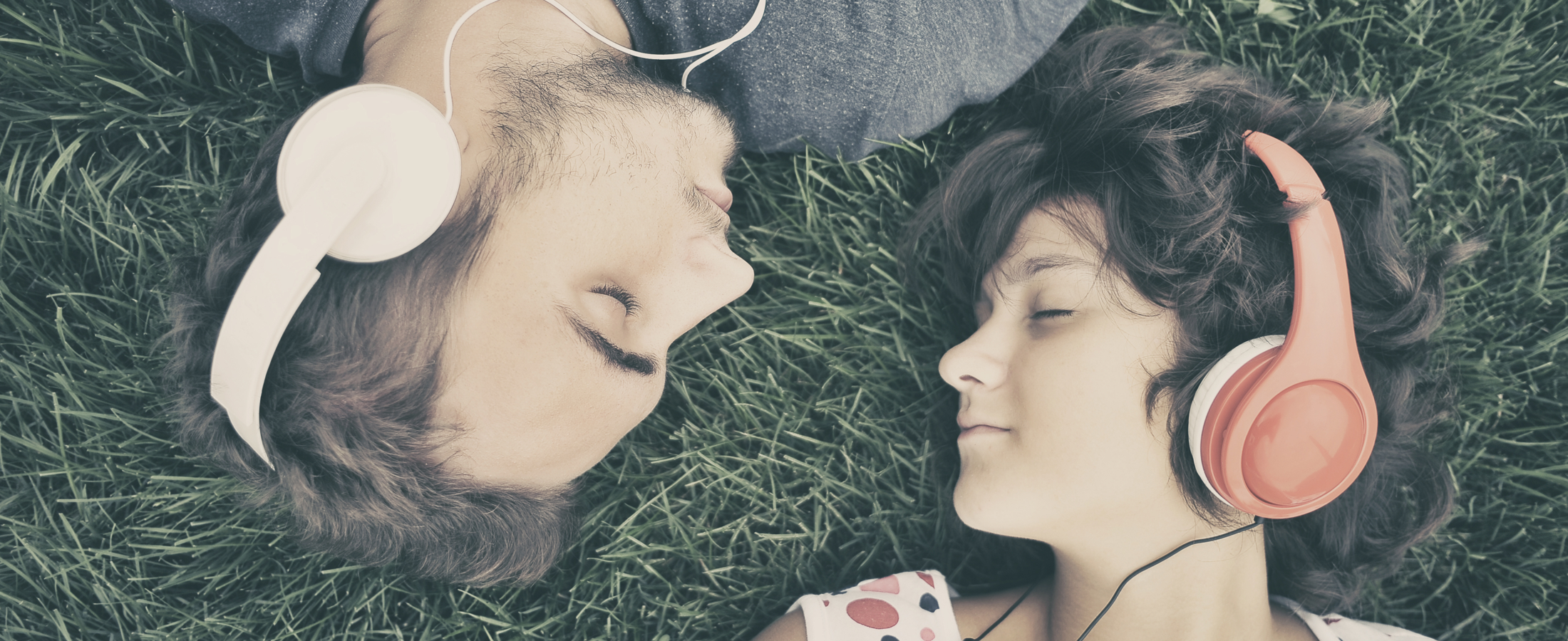 Pareja escuchando música, tumbados en el pasto