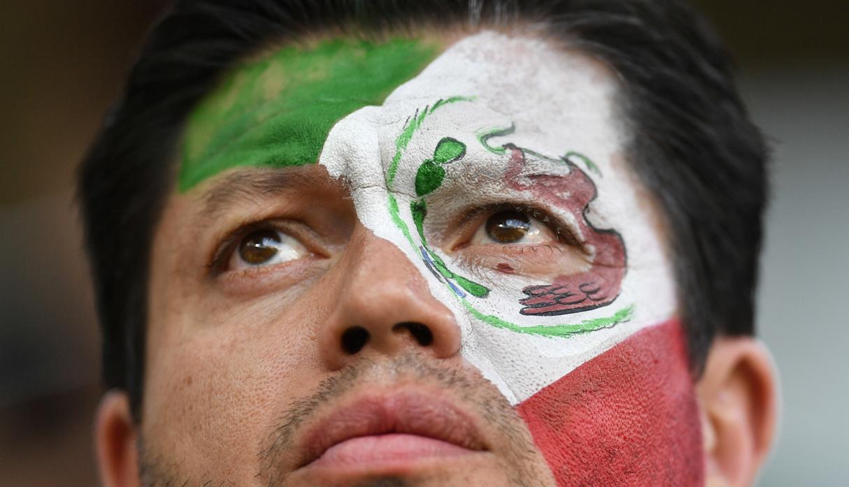 Hombre con bandera mexicana pintada en la cara.