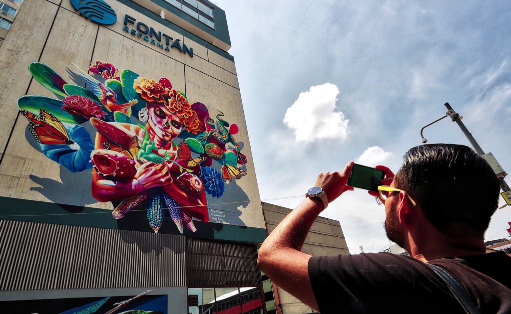 Transeúnte toma foto de mural de la Catrina, Ciudad de México