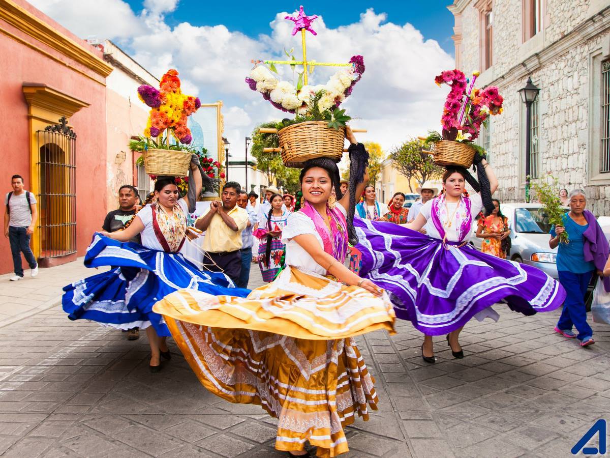 Mujeres bailando y portando trajes típicos de Oaxaca