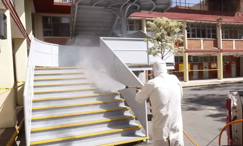 Protector contra hongos desinfectando escaleras con vapor, control de plagas en áreas públicas.