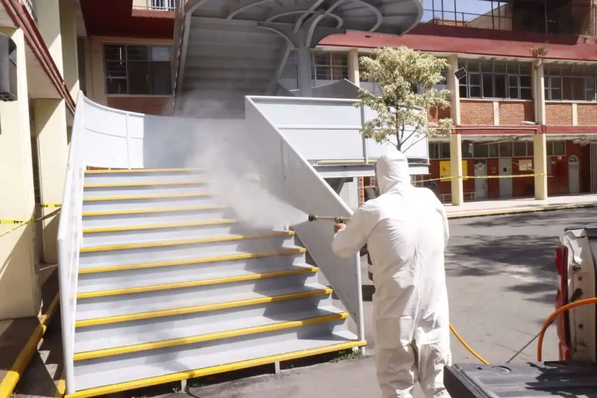 Protector contra hongos desinfectando escaleras con vapor, control de plagas en áreas públicas.