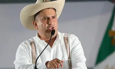 Hombre político en conferencia con sombrero mexicano en escenario.