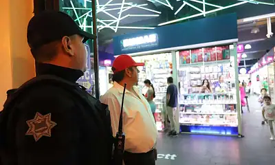 Vigilante de seguridad en shopping center con luces de neón.