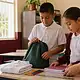 Estudiantes de primaria preparan uniformes y útiles escolares en un salón de clases.