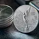 Onza de plata Libertad junto a pesos y dólares durante una semana de alzas en el mercado internacional de metales.