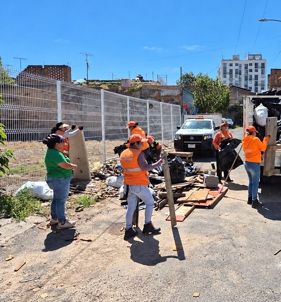 Personal de Guadalajara Limpia retira basura y objetos acumulados durante un operativo de limpieza en la vía pública.